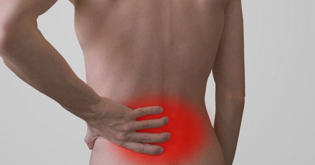 Man experiencing lower back pain with highlighted area in red